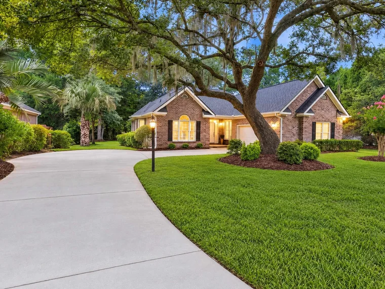 Brick single-story home with a curved driveway under a live oak at 97 Portrush Loop, Pawleys Island, SC.